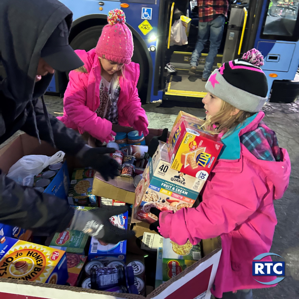 Image of children helping to unload food donations from RTC bus.