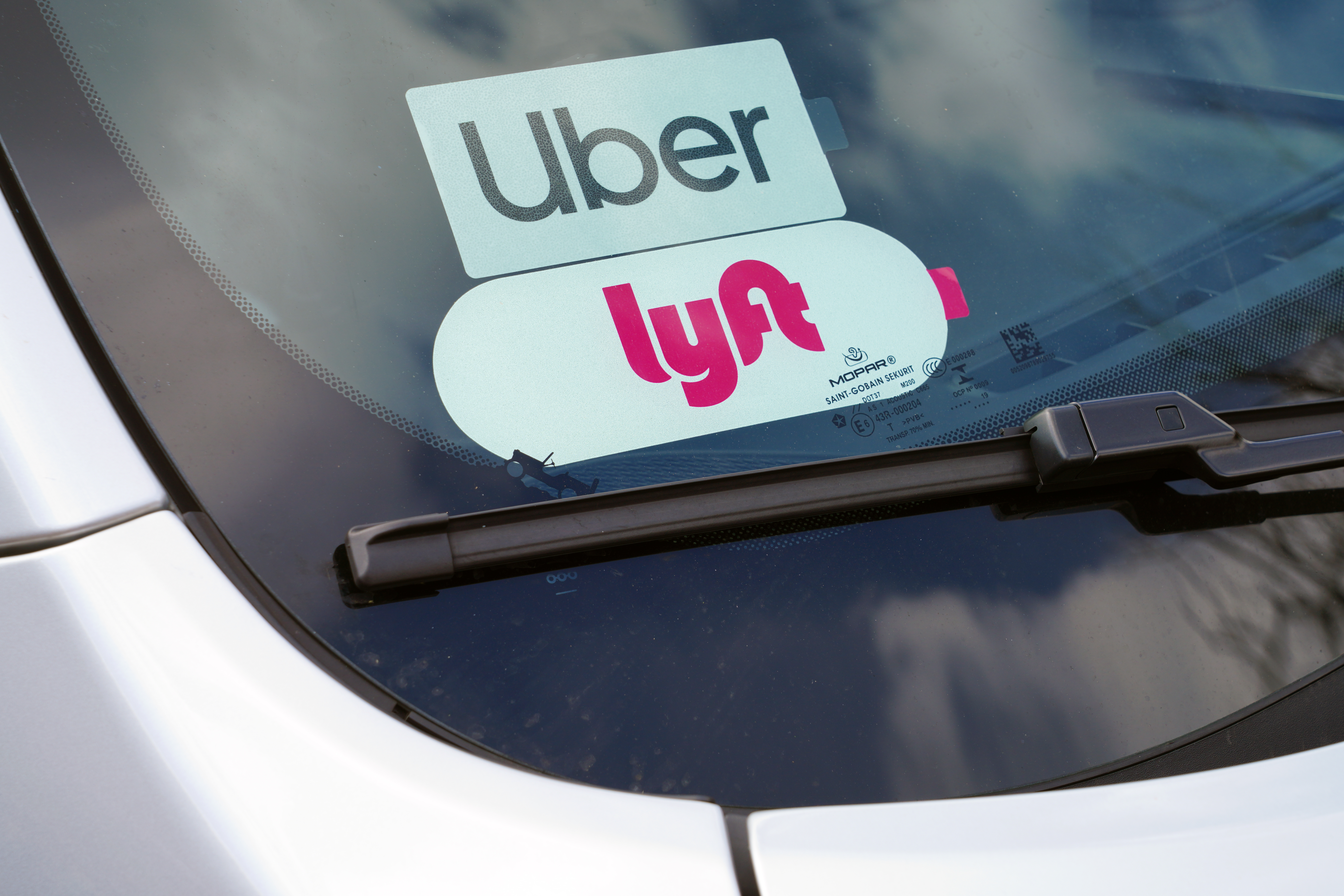 View of a car with stickers for both the Uber and Lyft ride share service on the windshield