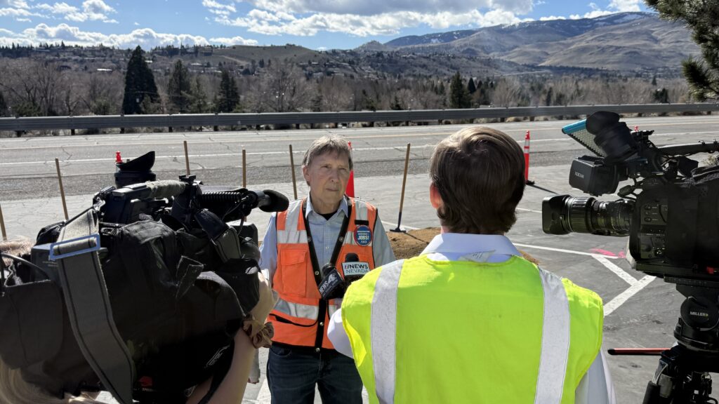 RTC Project Manager Scott Gibson speaks with local television news crews following the groundbreaking ceremony. Gibson is interviewed on the project site with snow-capped Sierra Nevada mountains visible in the background.